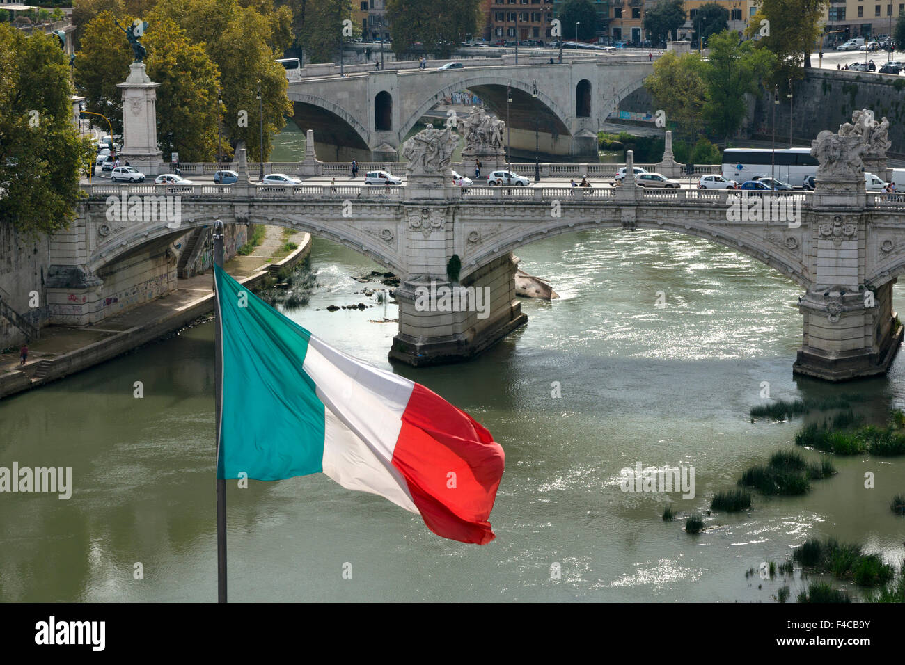 Bandera italiana sobrevolando el río Tiber con el puente de Sant'Angelo, Roma, Italia Foto de stock