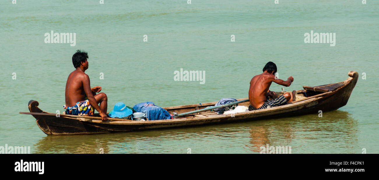 Dos hombres asiáticos remando en un barco de madera de río Foto de stock