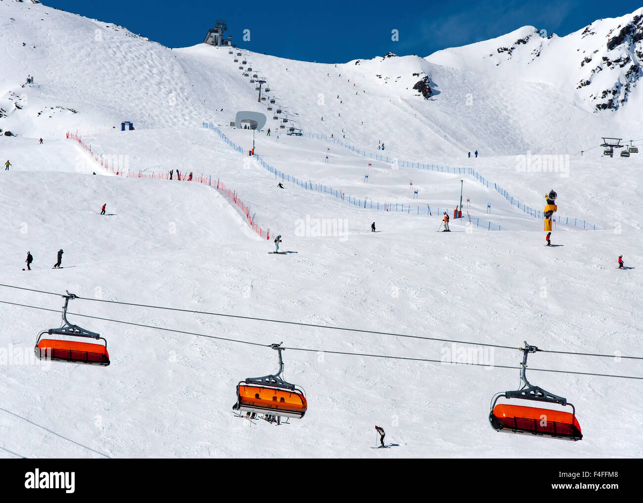 Los esquiadores, telesilla naranja y curso de slalom en la estación de esquí alpino en Solden en Otztal Alpes, Tirol, Austria Foto de stock