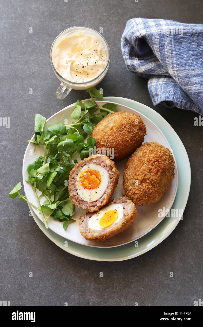 Scotch huevos en un plato con berros ensalada y mayonesa dip Foto de stock