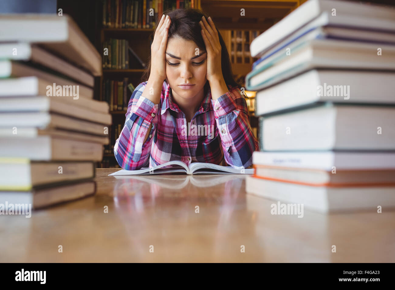 Frustrado estudiante con pila de libros Foto de stock
