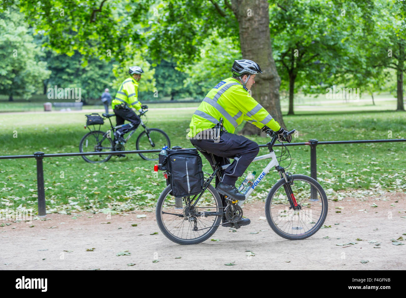 Dos policías en bicicleta patrullando en St James's Park por el Mall, Londres, Inglaterra Foto de stock