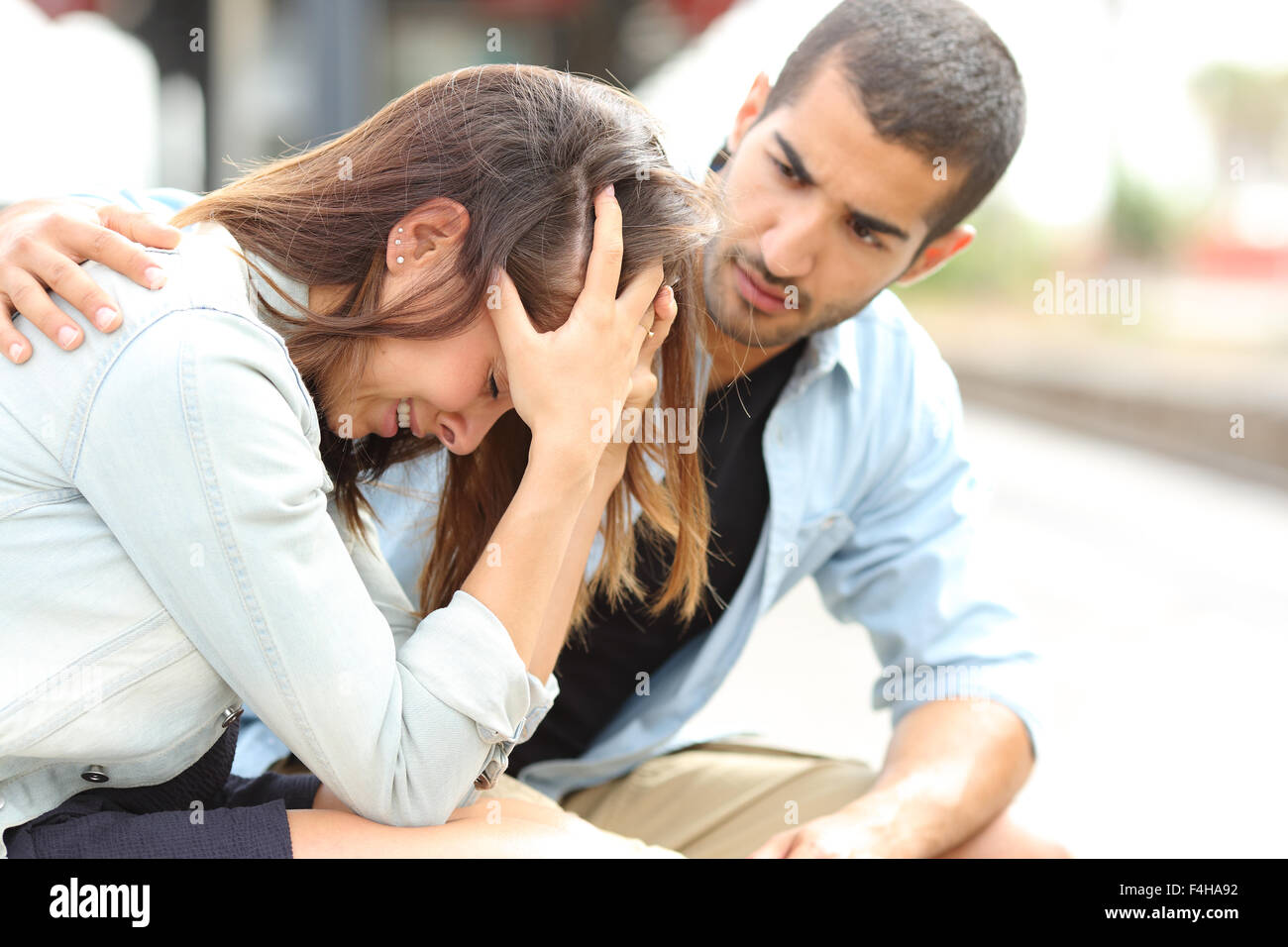 Vista lateral de un hombre musulmán un triste consuelo chica caucásica duelo en una estación de tren Foto de stock