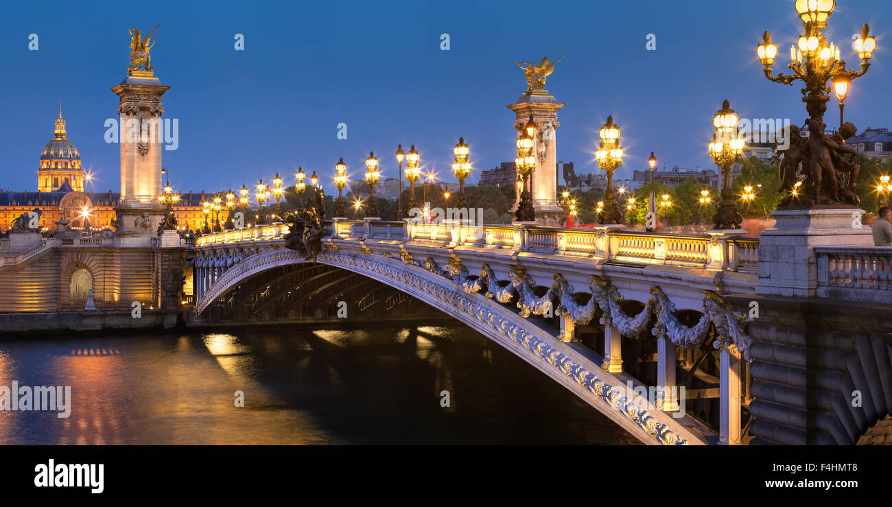 Pont Alexandre III (siglo xix, Beaux-Arts estilo arquitectónico), el río Sena y Les Invalides en penumbra, París, Francia Foto de stock