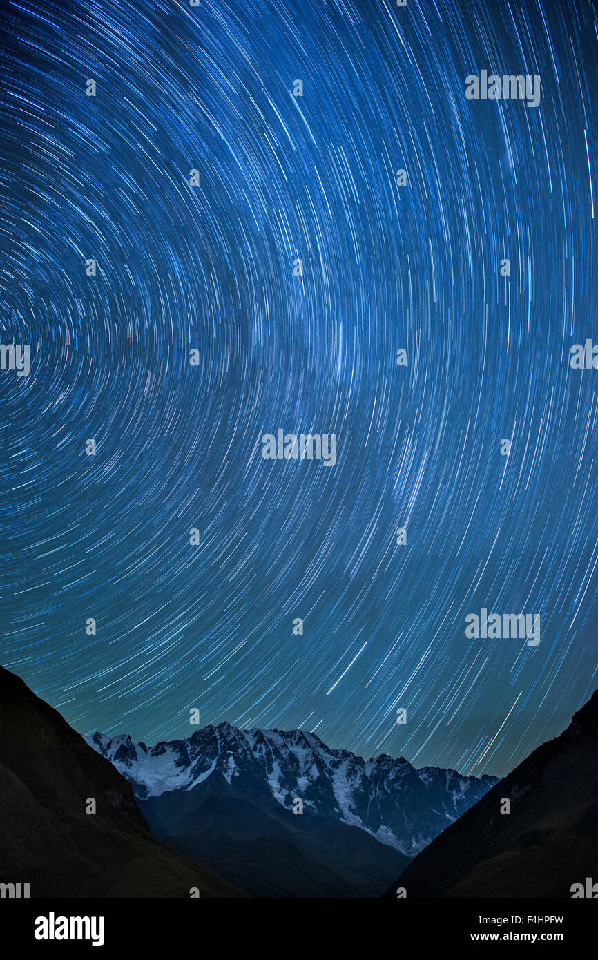 Moonlit vista de Estelas de estrellas sobre el Monte Shkhara (5193m), la montaña más alta de Georgia. Foto de stock