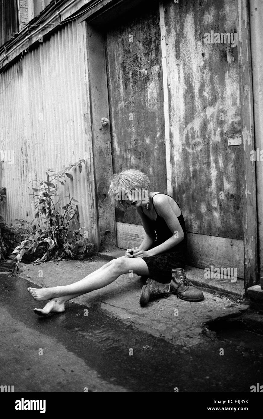 Mujer joven sentada fuera de edificios Foto de stock