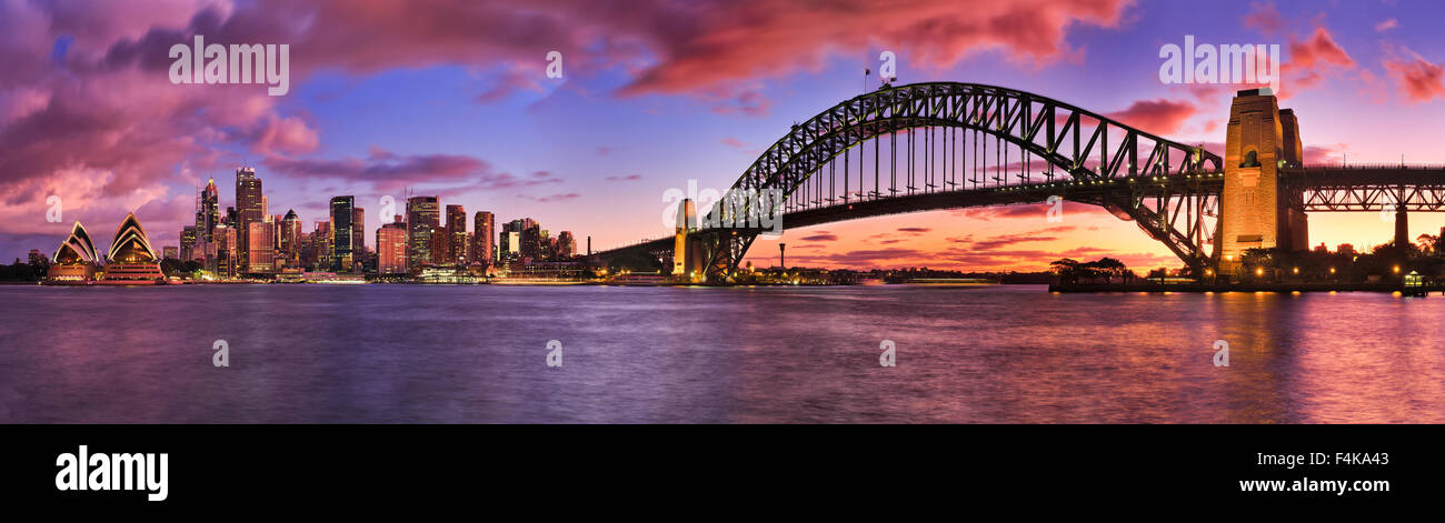 Quema luminoso atardecer en Sydney CBD cityline panorámicamente representada a través de puerto incluyendo rascacielos y Harbour Bridge Foto de stock