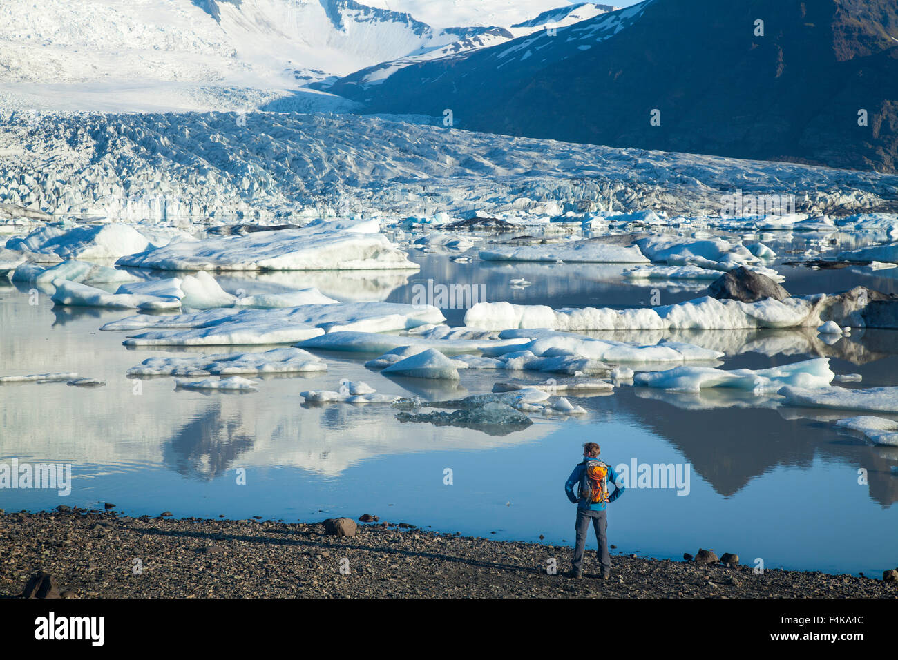 Persona junto a Fjallsarlon iceberg, debajo de la laguna glaciar Fjallsjokull. Parque Nacional Vatnajokull, Sudhurland, Islandia. Foto de stock