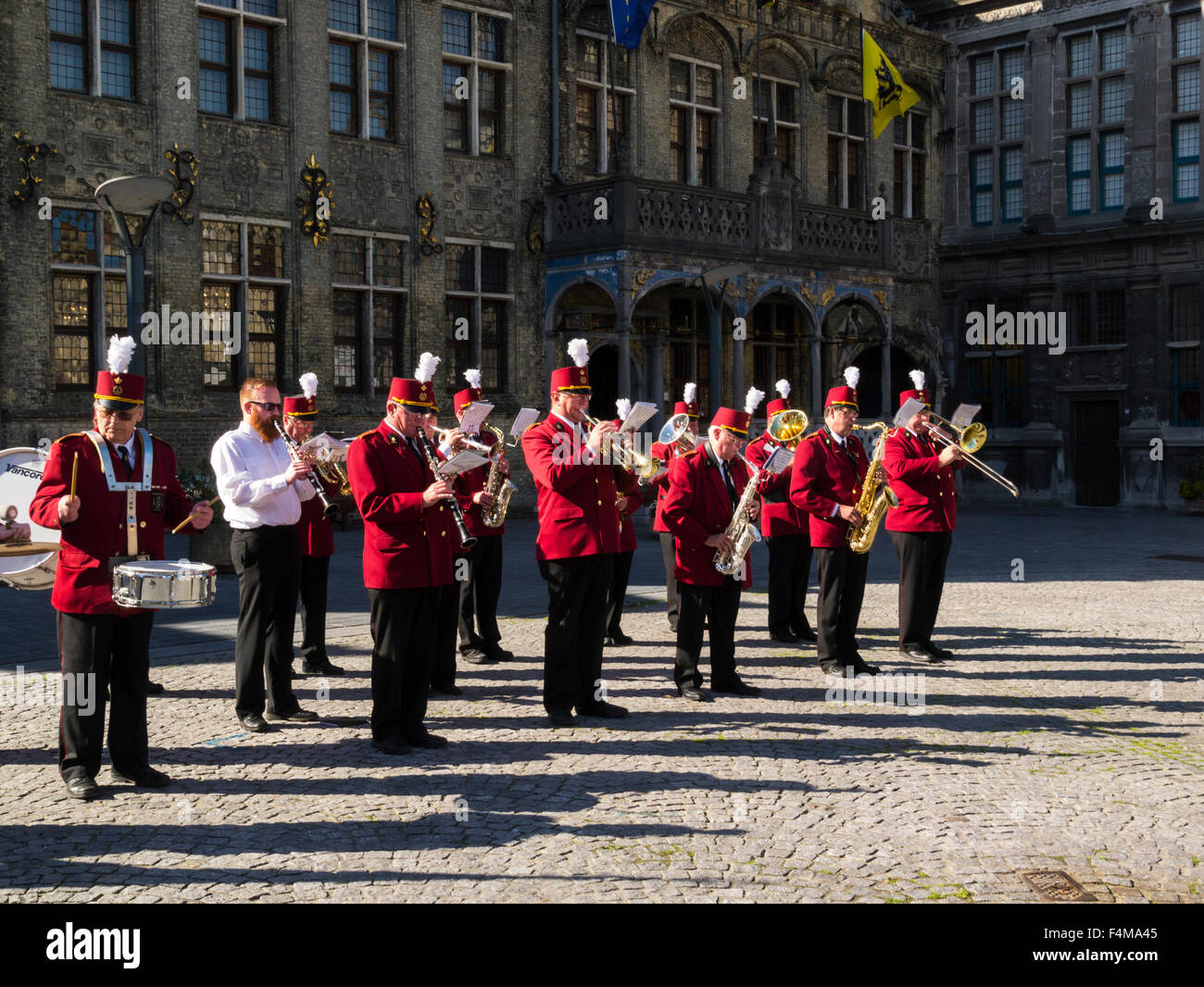 Santa Cecilia Kon Harmonie banda en uniformes rojos entretenido visitantes Grote Markt, la plaza del mercado Veurne Flandes Occidental Bélgica Sitio de Patrimonio Mundial de la UNESCO Foto de stock