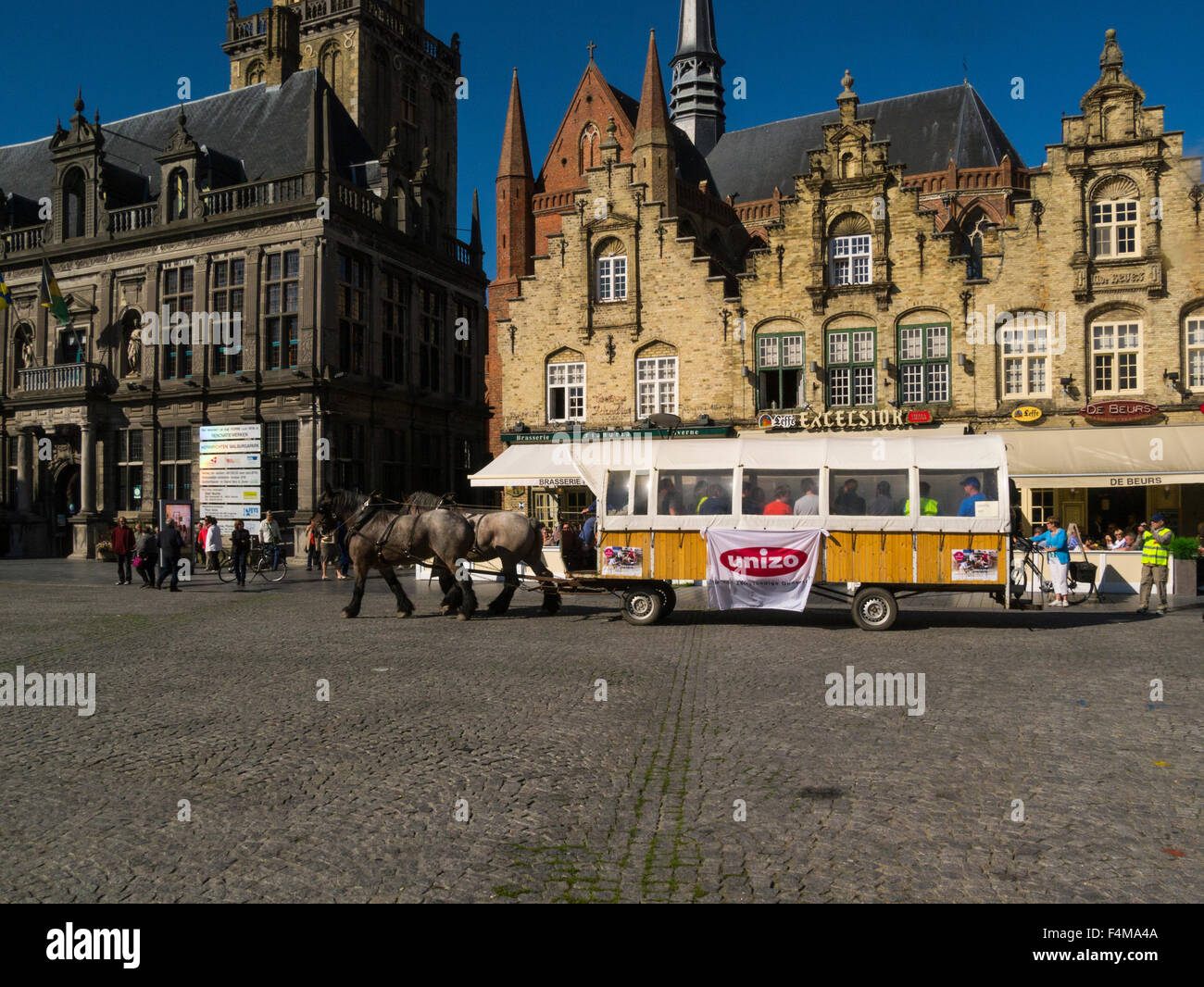 Caballo dibujado el transporte de turistas en la plaza del mercado Grote Markt empedradas Veurne Flandes Occidental Bélgica Sitio de Patrimonio Mundial de la UNESCO, antiguo edificio de juzgados Foto de stock