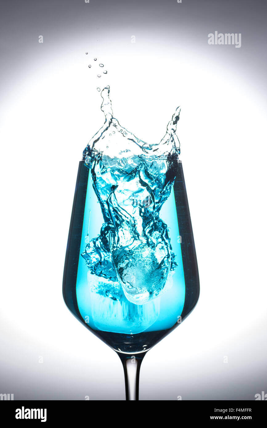 Copa de Vino aislado sobre fondo blanco con salpicaduras de agua de un cubo de hielo Foto de stock