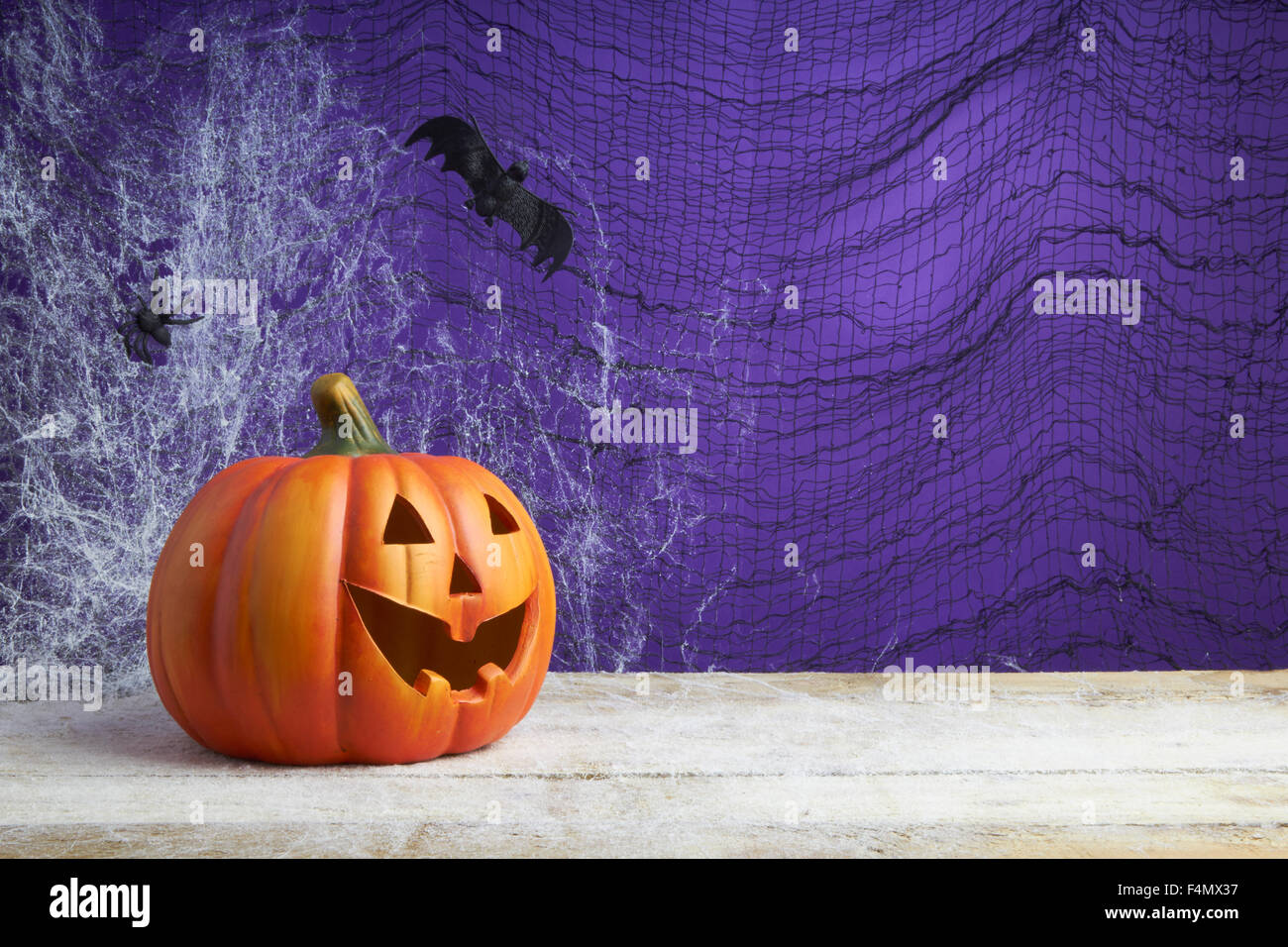 Concepto de Halloween con un jack o lantern calabaza, araña de juguete y bat en una telaraña de fondo oscuro Foto de stock