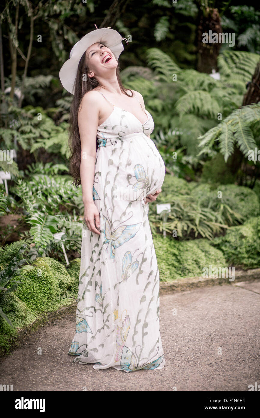 Retrato de mujer embarazada vistiendo ropa de verano y sombrero en un  invernadero permanente Fotografía de stock - Alamy