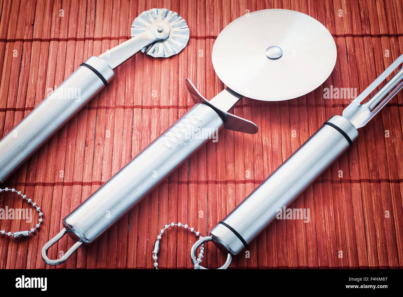 Conjunto de nuevas herramientas de cocina de acero inoxidable en el Rojo fondo de bambú. Foto de stock