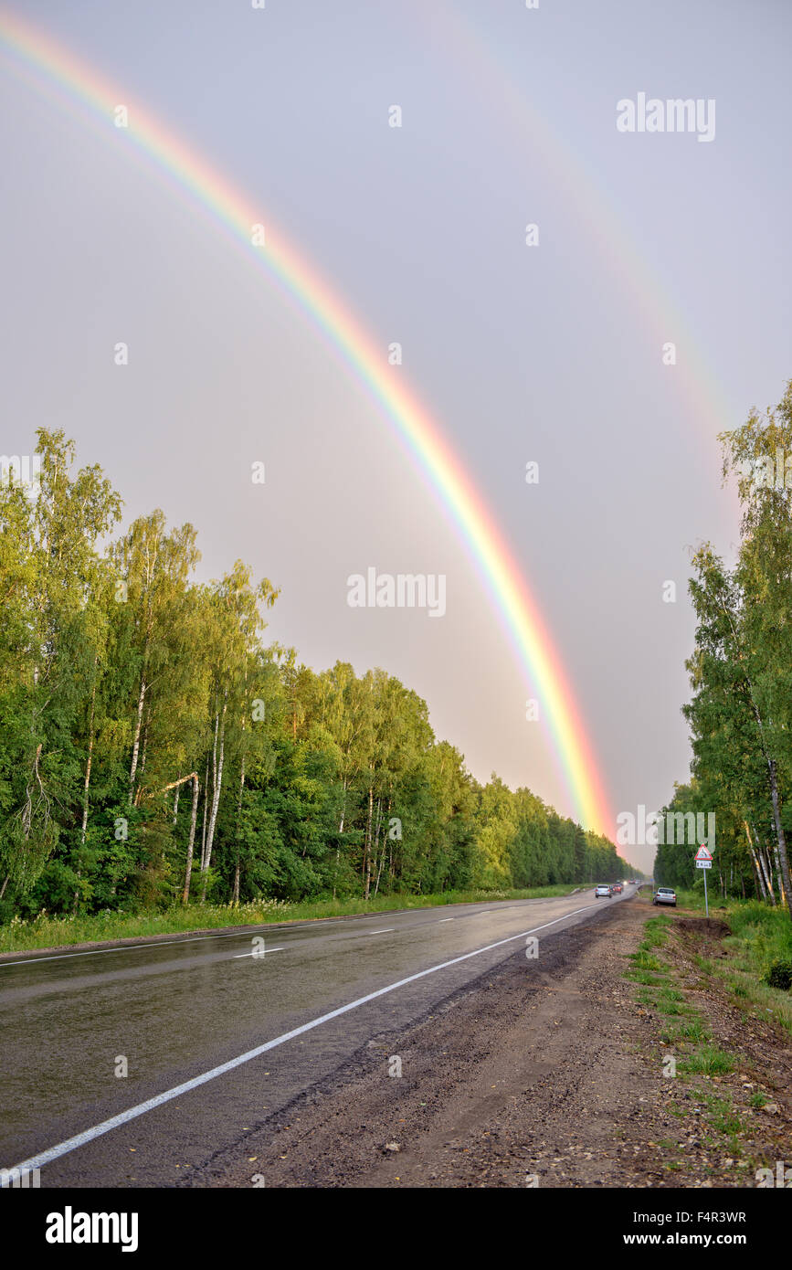 Doble arco iris en el cielo sobre el camino y el bosque Fotografía de stock  - Alamy