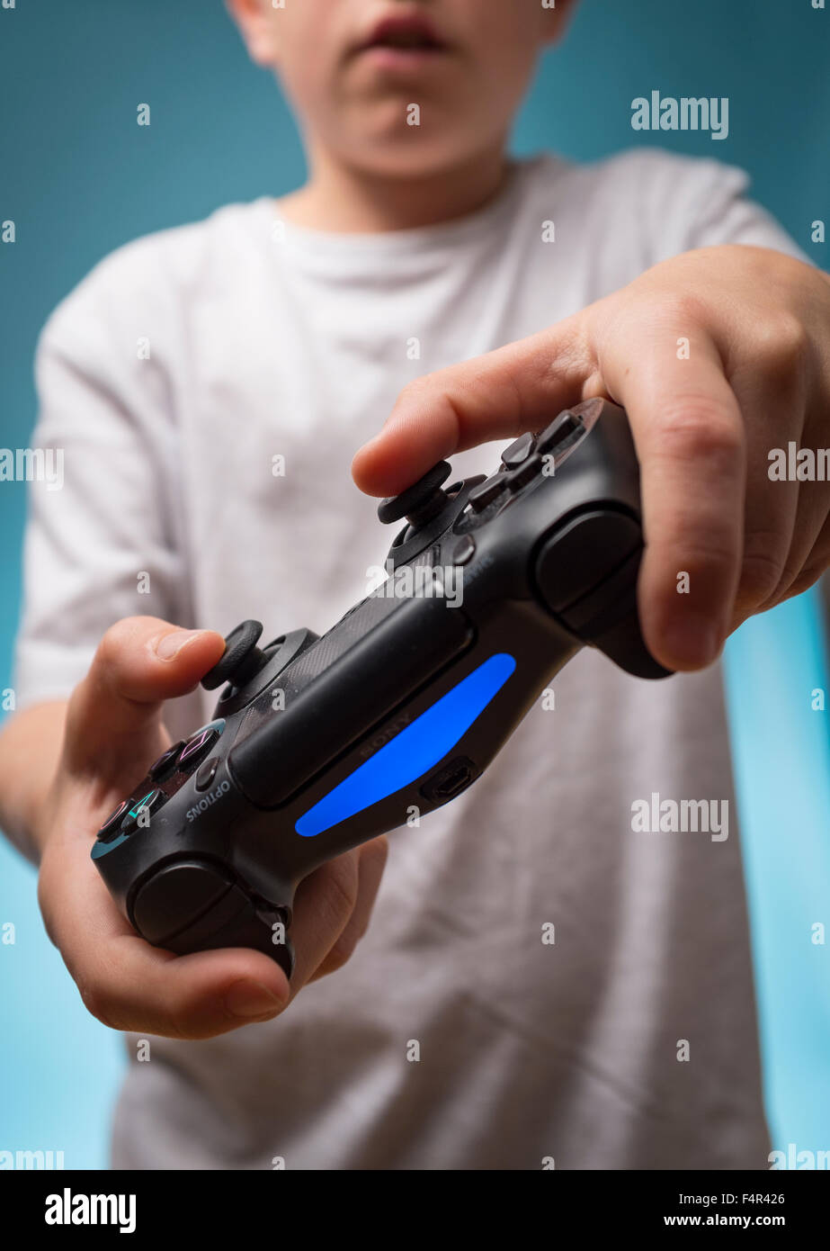 Un niño que está jugando los juegos de ordenador con un controlador de PS4, Playstation 4 Foto de stock