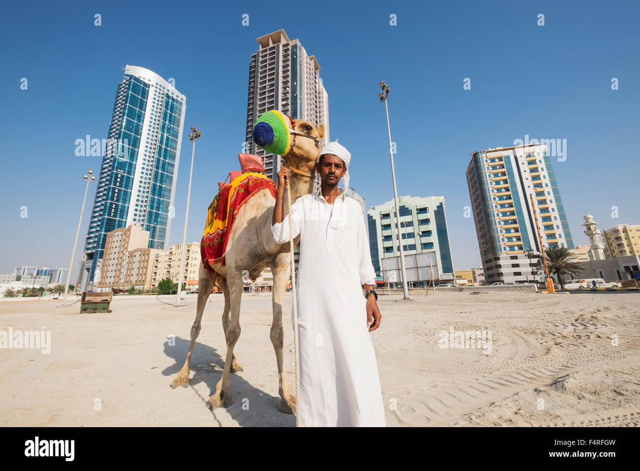Hombre con camel caminando por la playa en la costa del emirato de Ajman, en los Emiratos Árabes Unidos Foto de stock