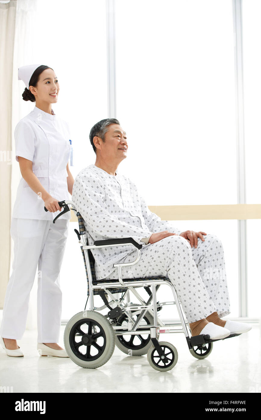 La enfermera empujó al anciano en una silla de ruedas. Foto de stock