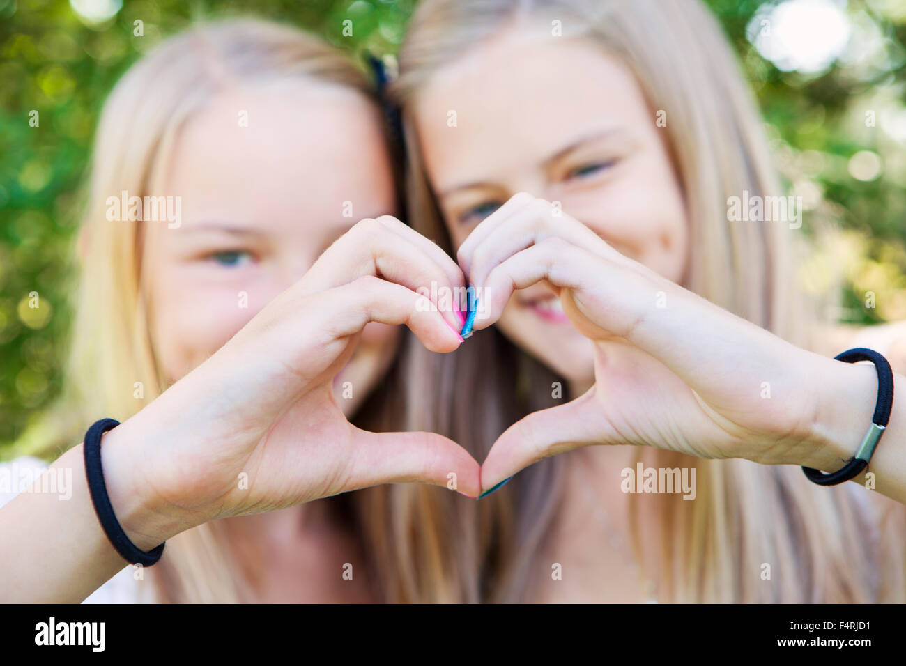 Amigas (12-13) y el gesto con forma de corazón Foto de stock