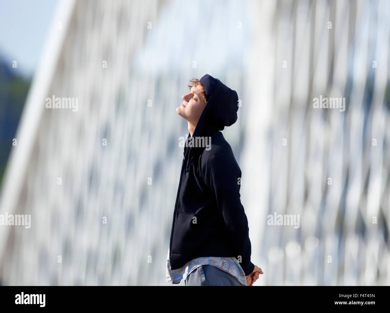 Joven con capucha de pie en el puente Foto de stock