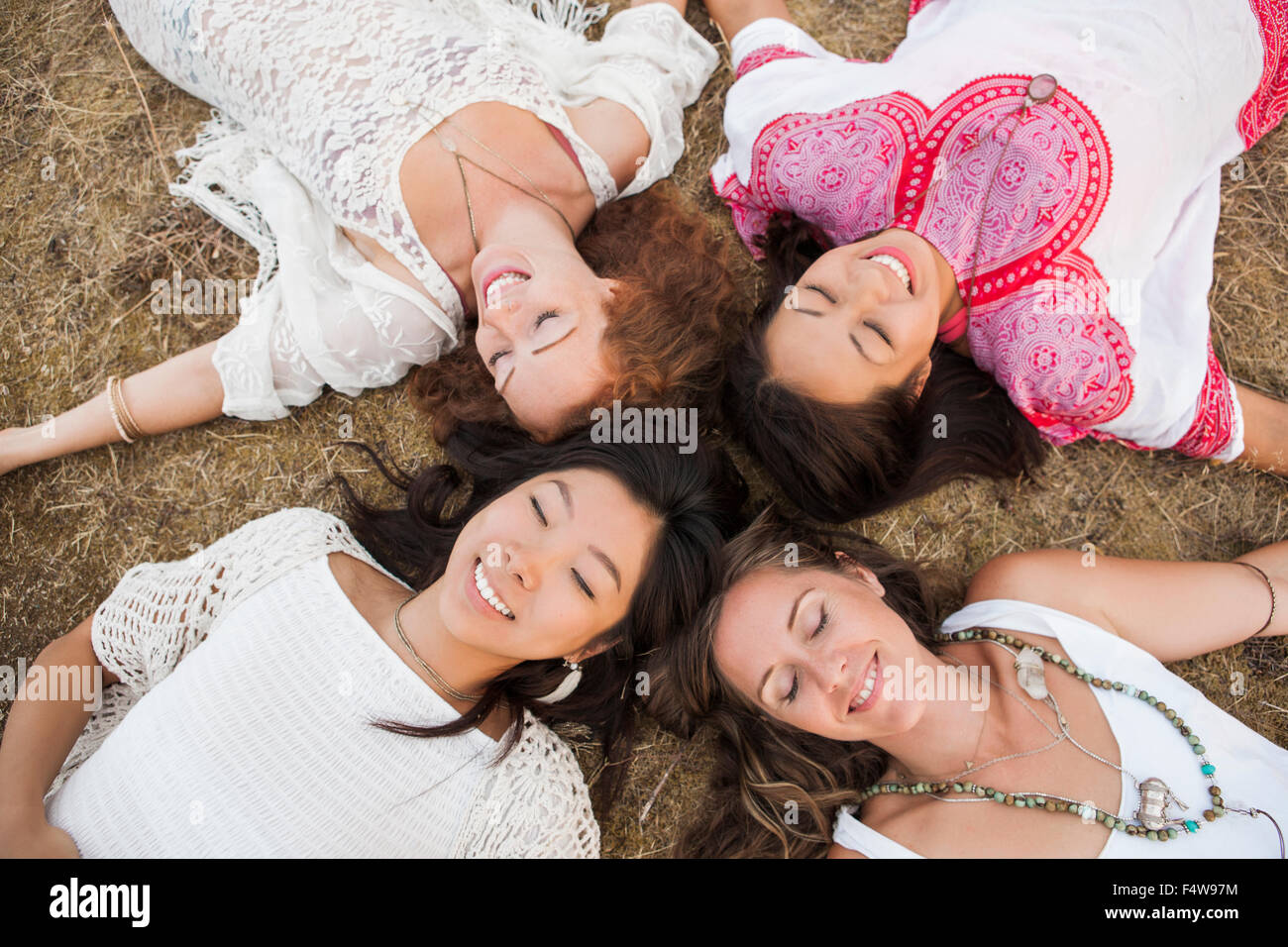 Vista aérea de sonrientes mujeres boho sentando en círculo con los ojos cerrados Foto de stock