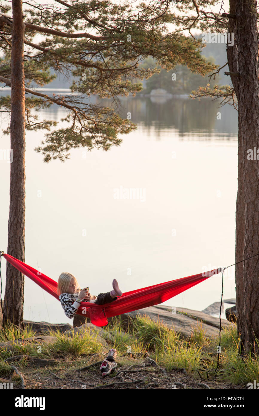 Suecia, Vastergotland, Harskogen, Stora Harsjon, Girl (10-11) relajarse en una hamaca en el lago Foto de stock