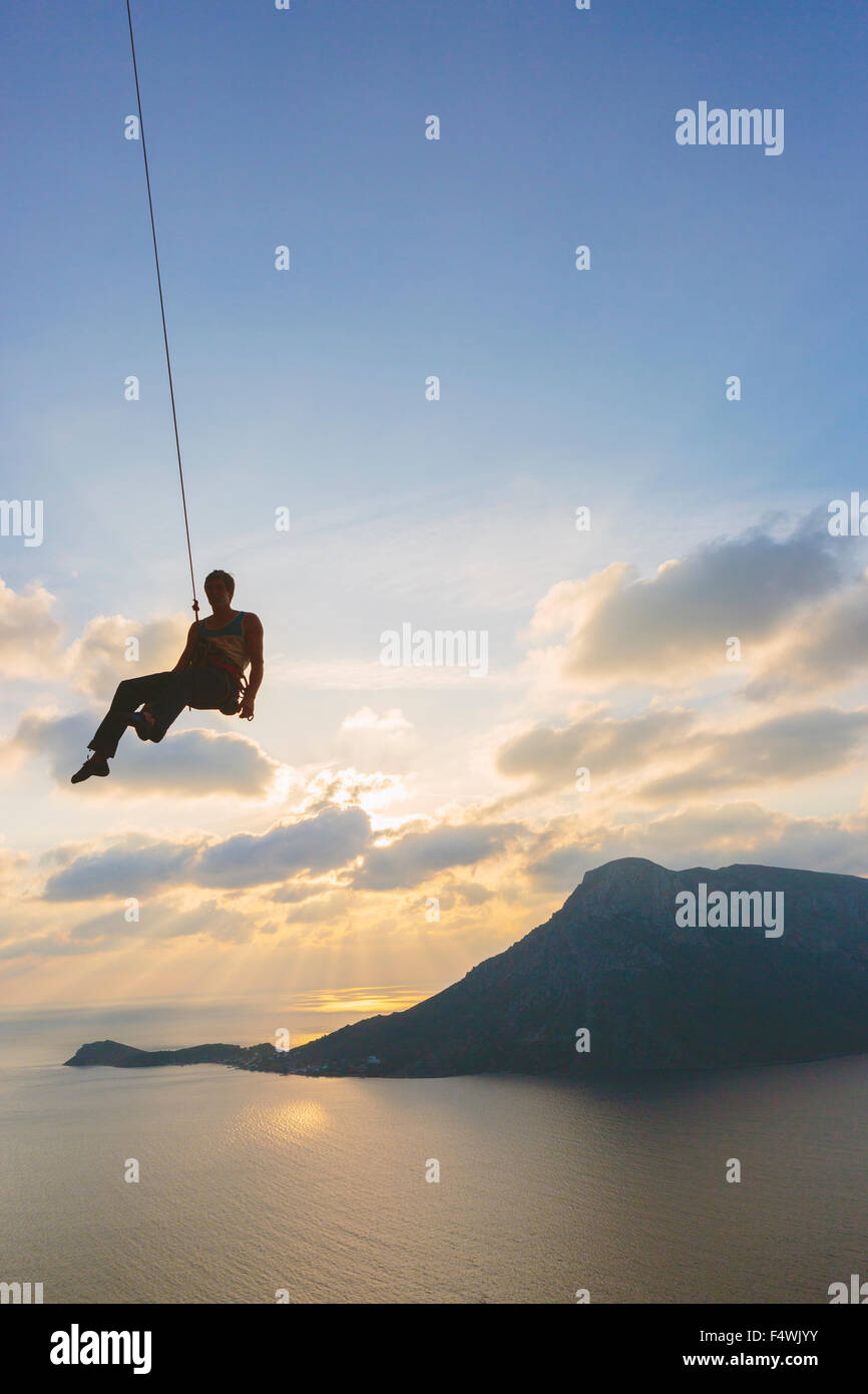 Grecia, Dodecaneso, Kalymnos, hombre de entregar la cuerda de escalada contra el cielo Foto de stock