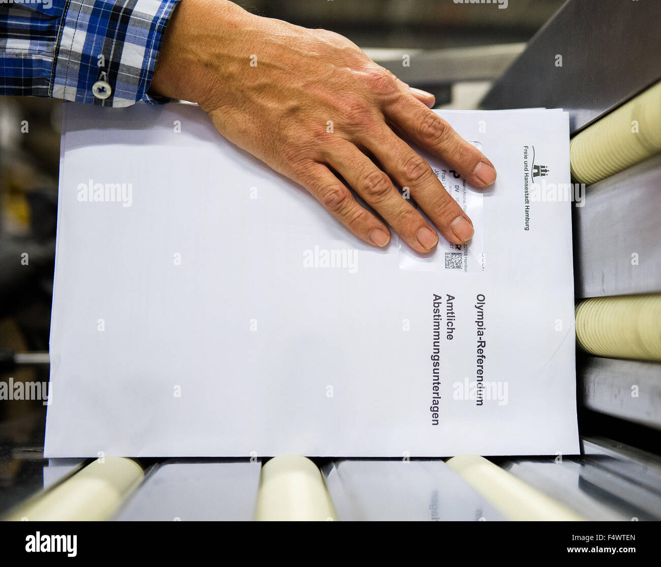 Hamburgo, Alemania. 23 Oct, 2015. Un hombre sostiene sobres durante una conferencia de prensa en un centro de distribución de correo para el inicio de los Juegos Olímpicos referéndum, detrás de una caja con documentos oficiales de votación en Hamburgo, Alemania, 23 de octubre de 2015. El referedum va hasta el 29 de noviembre de 2015 para decidir sobre la solicitud de Hamburgo para los Juegos Olímpicos y Paralímpicos de 2024. Foto: DANIEL BOCKWOLDT/dpa/Alamy Live News Foto de stock