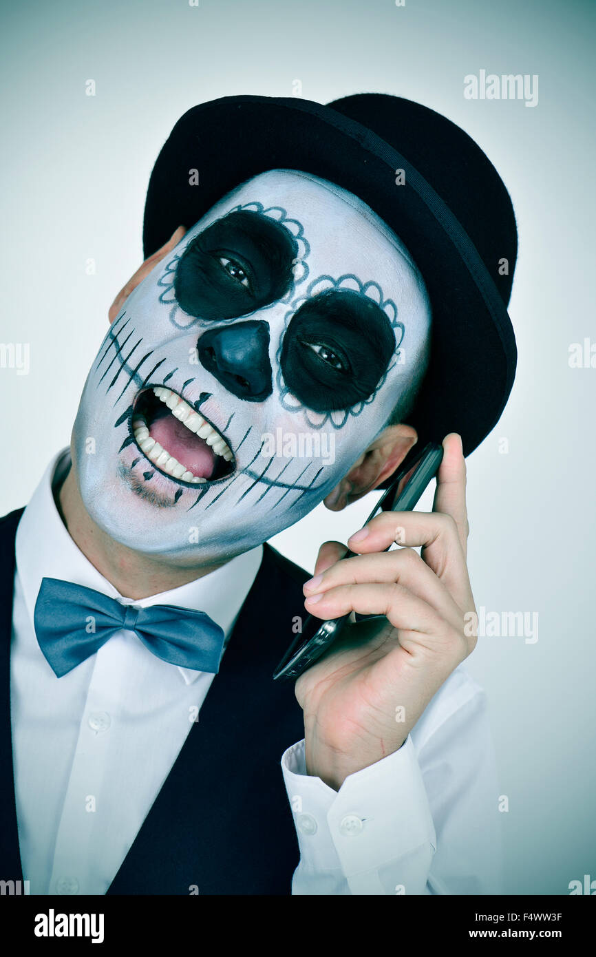Retrato de un hombre con el maquillaje, calaveras mexicanas luciendo  pajarita y sombrero de copa, en el teléfono Fotografía de stock - Alamy