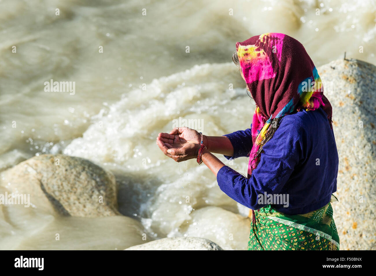 Una hembra de peregrino en los bancos del río Ganges está orando, ofreciendo el agua bendita Foto de stock