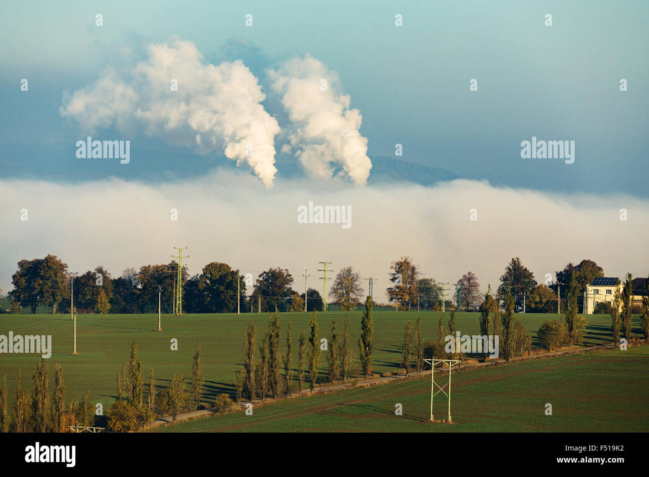 No fumar ecologic chimeneas en desde la fábrica oculta en niebla de la mañana a lo largo de paisaje rural Foto de stock