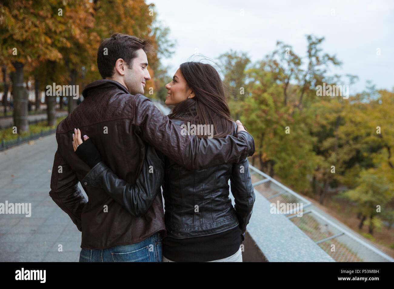 Vista posterior retrato de una pareja sonriente caminando en el parque de otoño Foto de stock