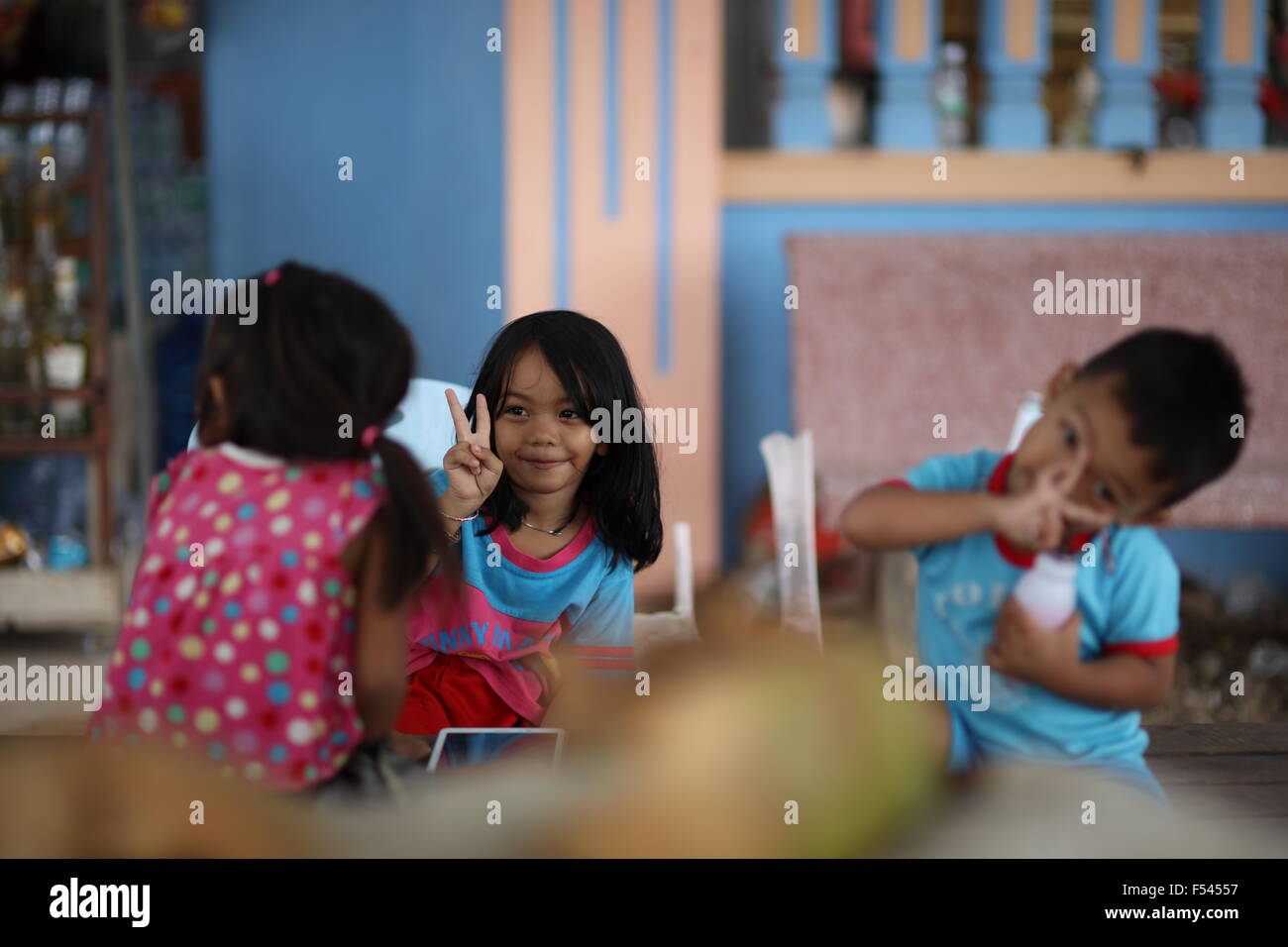 Girl in focus mostrando la victoria a otra niña, un chico intentando mimik su Foto de stock