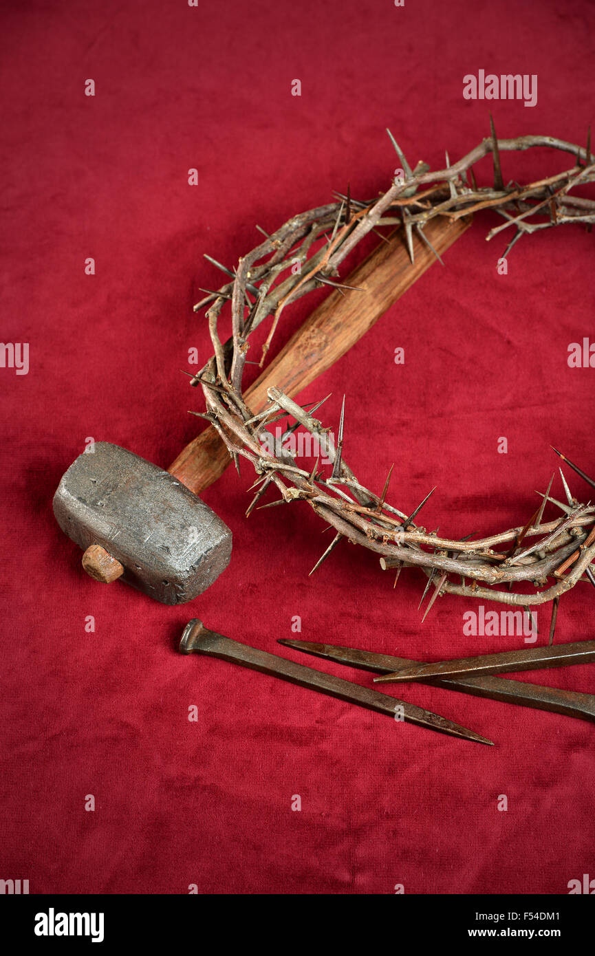 Corona de espinas, clavos y un martillo en el trapo rojo Foto de stock