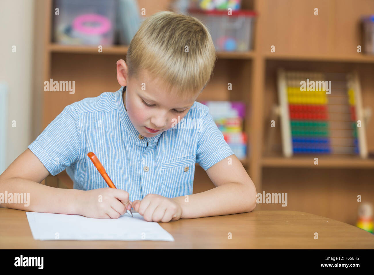 Concentra boy a escribir en papel en la mesa Foto de stock