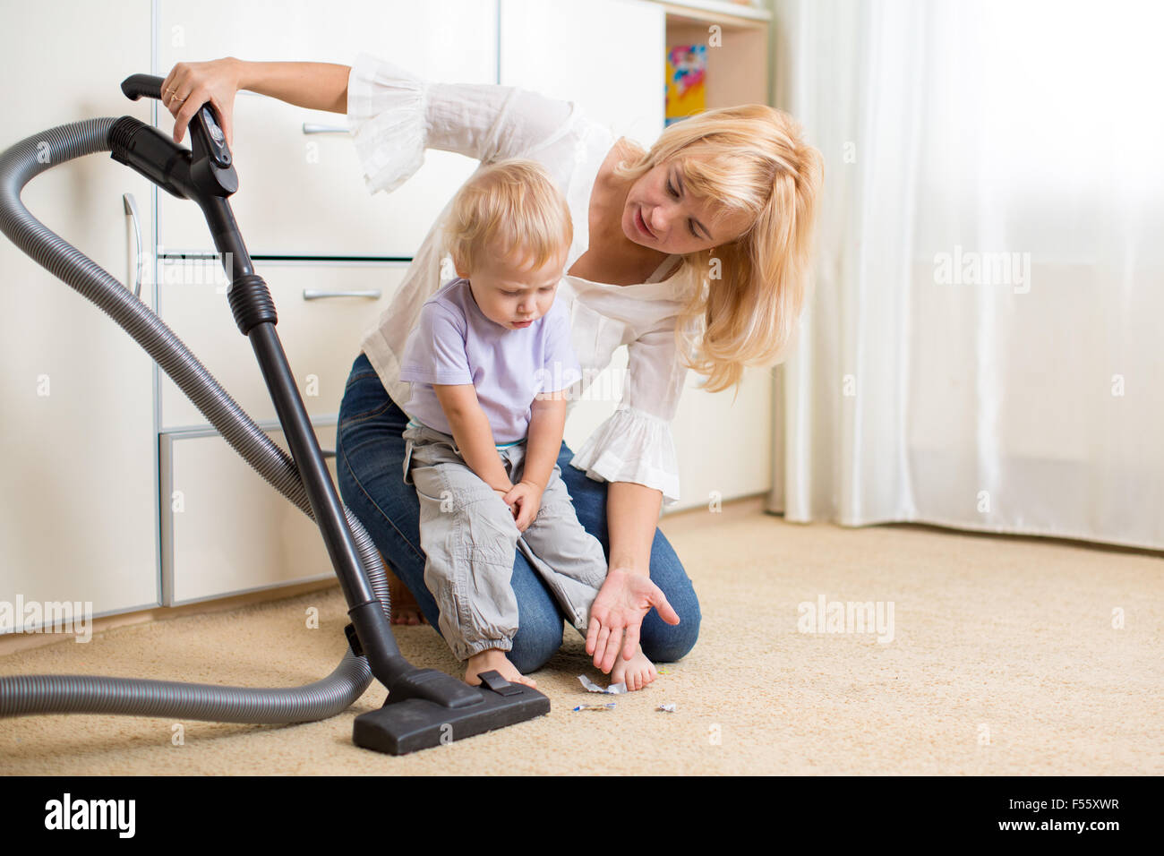 La madre enseña a su hijo hijo limpieza de habitación Foto de stock