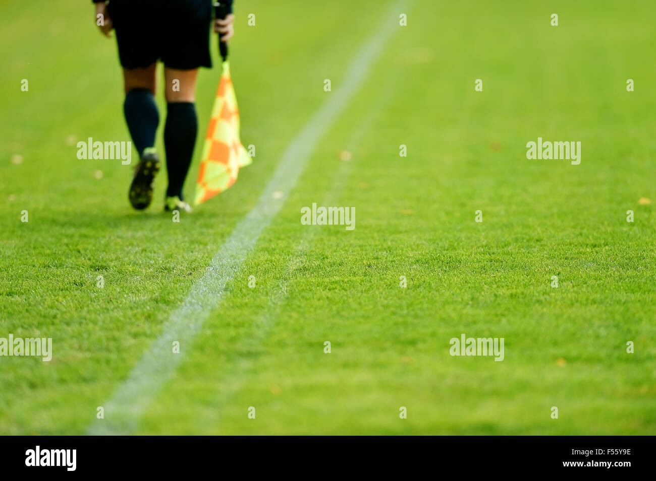 Árbitro asistente ejecutando junto al margen durante un partido de fútbol Foto de stock