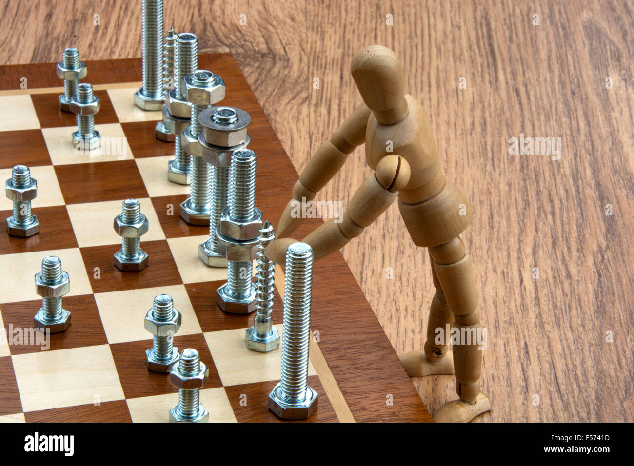 Maniquí de madera jugando al ajedrez con las piezas fabricadas desde tuercas  y tornillos Fotografía de stock - Alamy