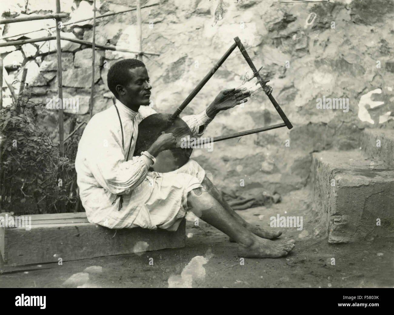 Un africano toca un instrumento musical de cuerdas triangular Foto de stock