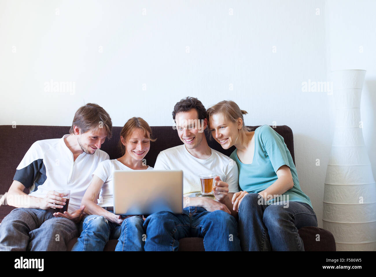 Un grupo de amigos, viendo la televisión y sonriente Foto de stock