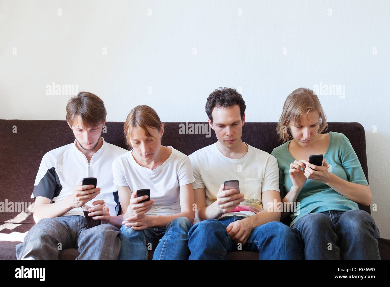 La adicción a Internet, un grupo de jóvenes que buscan en sus teléfonos inteligentes. Foto de stock