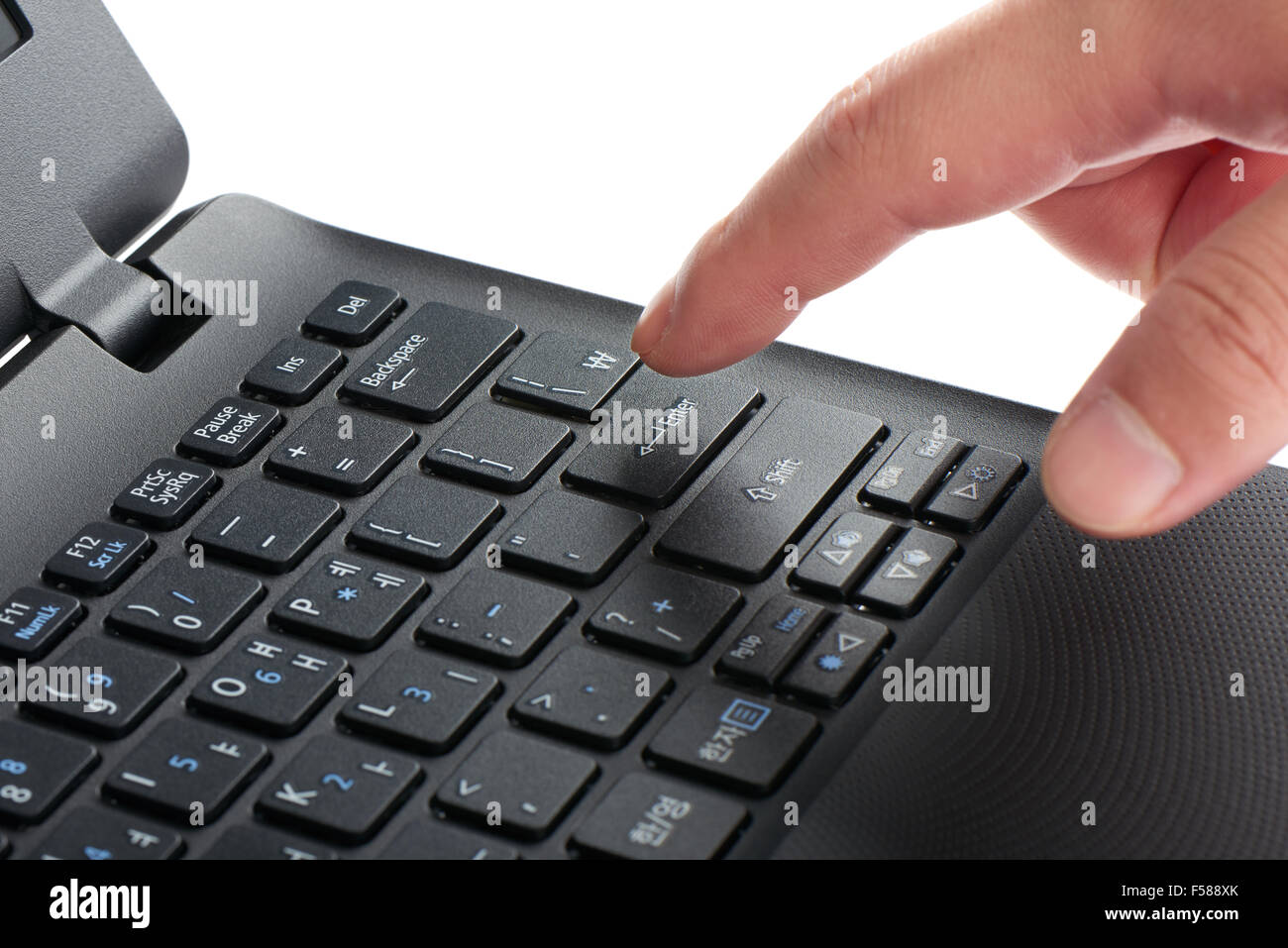 Primer plano de una laptop de teclado con el dedo índice presionando la tecla Intro, aislado en blanco Foto de stock