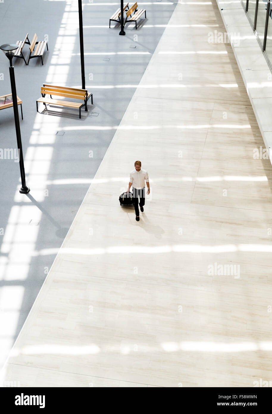 Guapo business sosteniendo un carro y caminar en un moderno edificio visto desde arriba Foto de stock