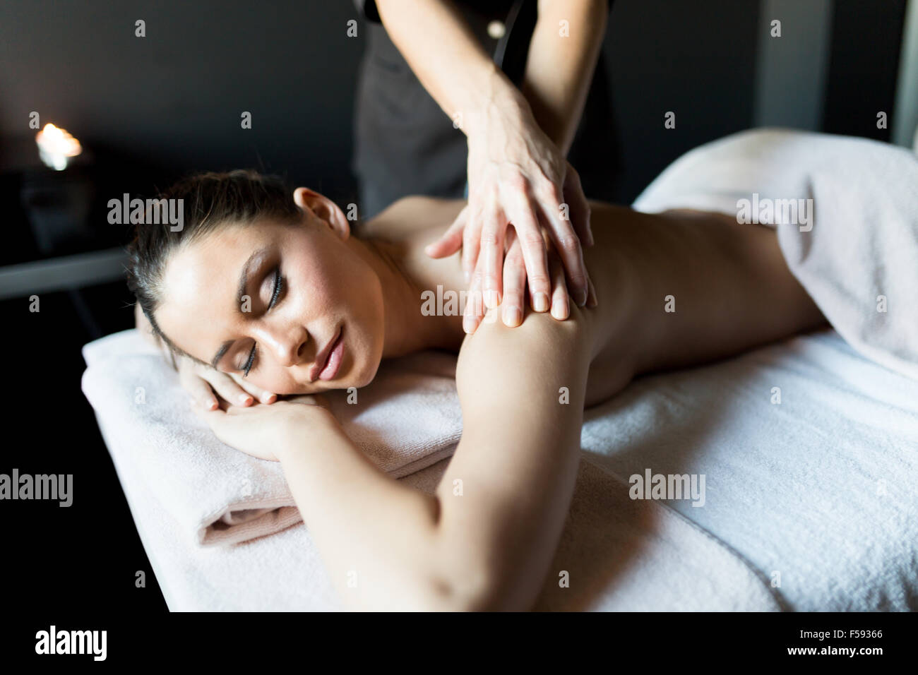 Hermosa, joven y mujer healty tras su hombro y cuerpo masajeado por un masajista profesional en un centro de spa Foto de stock
