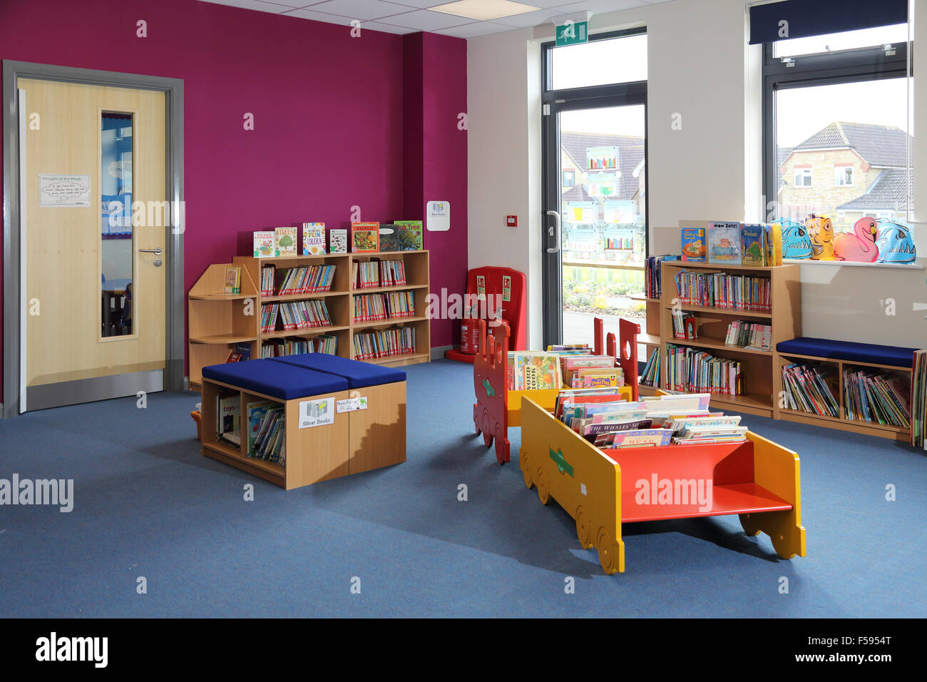 Área de biblioteca en una nueva escuela junior británica mostrando asientos y libros almacenados en el tradicional libro de casos y una mesa en forma de tren de vapor Foto de stock