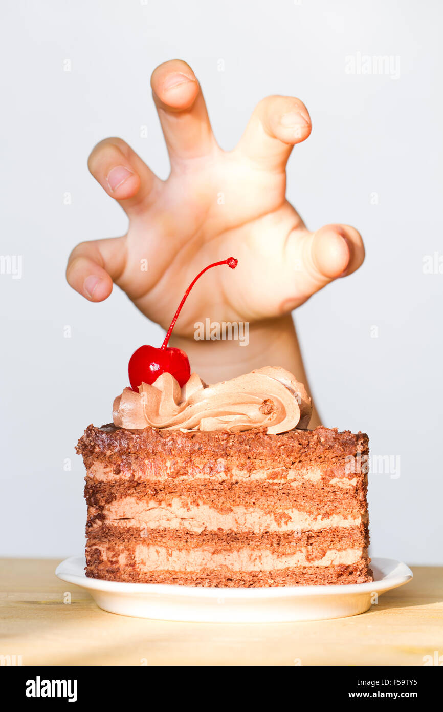 La codicia de los dulces concepto con la mano y pastel de chocolate concepto Foto de stock
