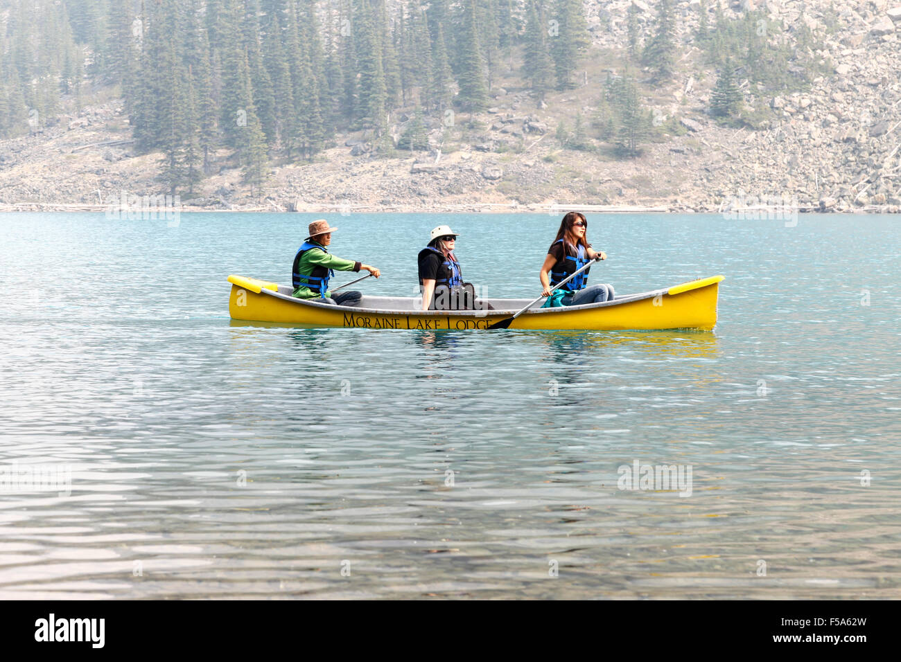 3 personas remando en una canoa en el lago Moraine Parque Nacional Banff Alberta Canada Foto de stock