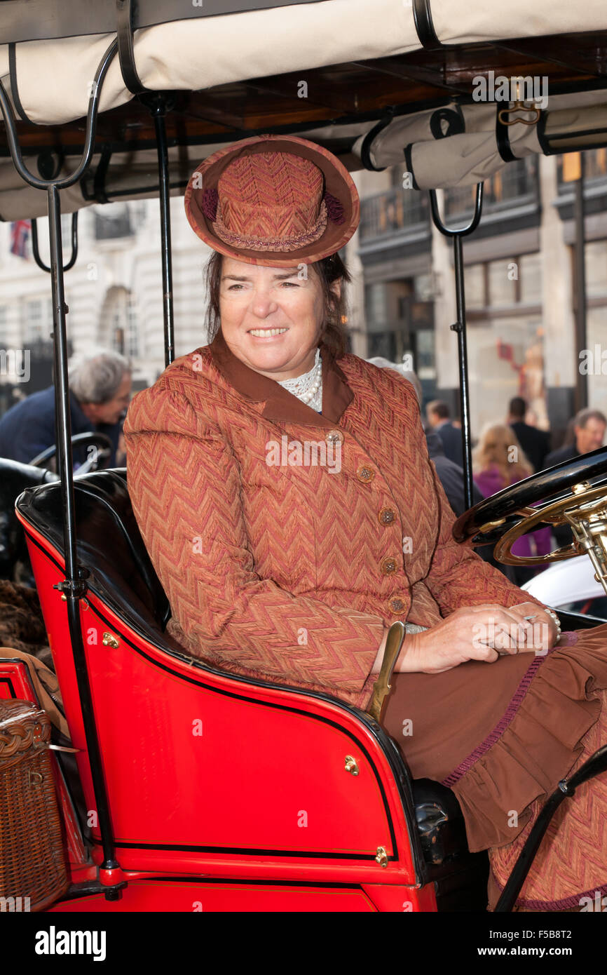 Una sonriente dama, con trajes de época, se sienta en un 1904 Rambler, como ella participa en el Concurso Internacional d'Elegance, Regents Street durante el Motor Show Foto de stock