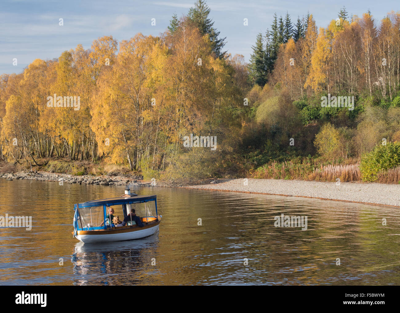 Disfruta de un viaje tranquilo en los alrededores de Loch Katrine en un pequeño barco de vapor en otoño Foto de stock