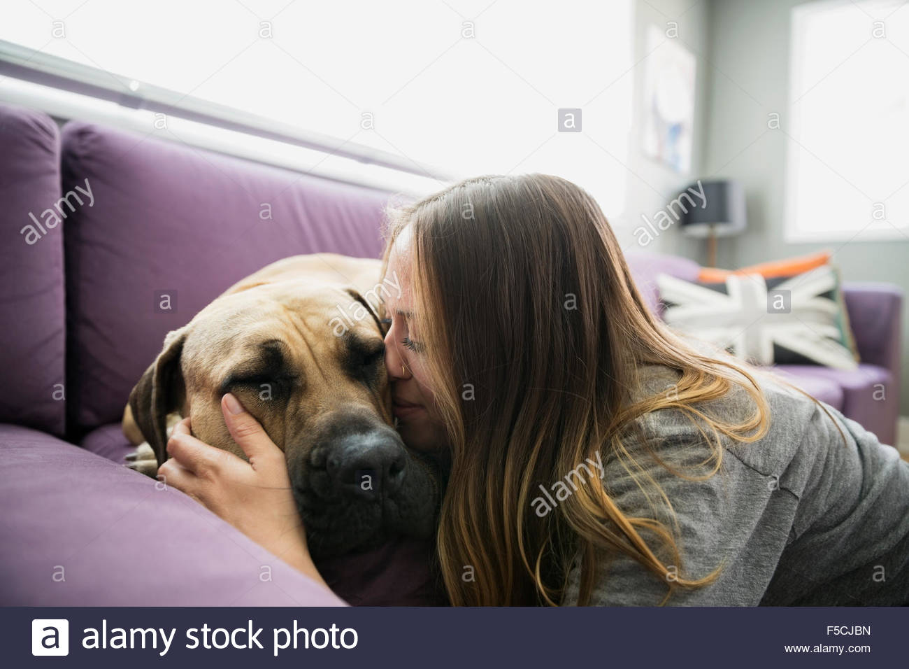 Besos mujer perro en la sala un sofá Foto de stock